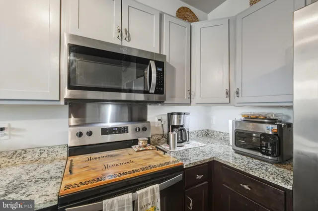 a kitchen with stainless steel appliances granite countertop a stove microwave and cabinets