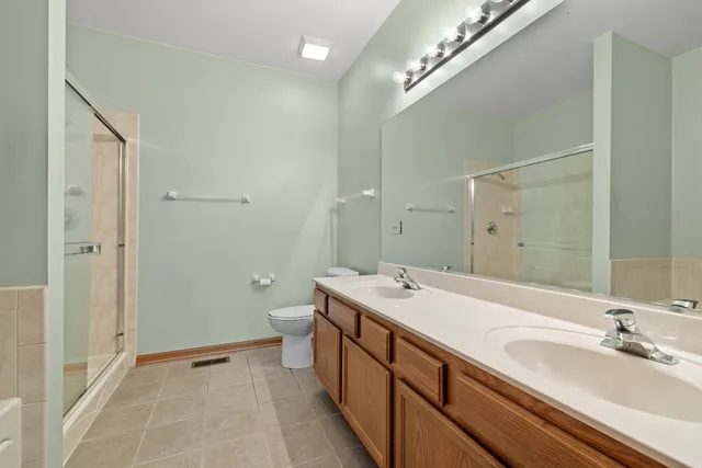 a spacious bathroom with a double vanity sink a large mirror and a shower