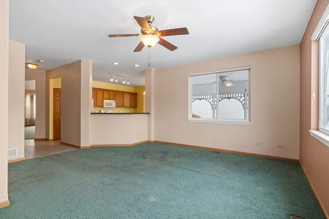 an empty room with ceiling fan and windows
