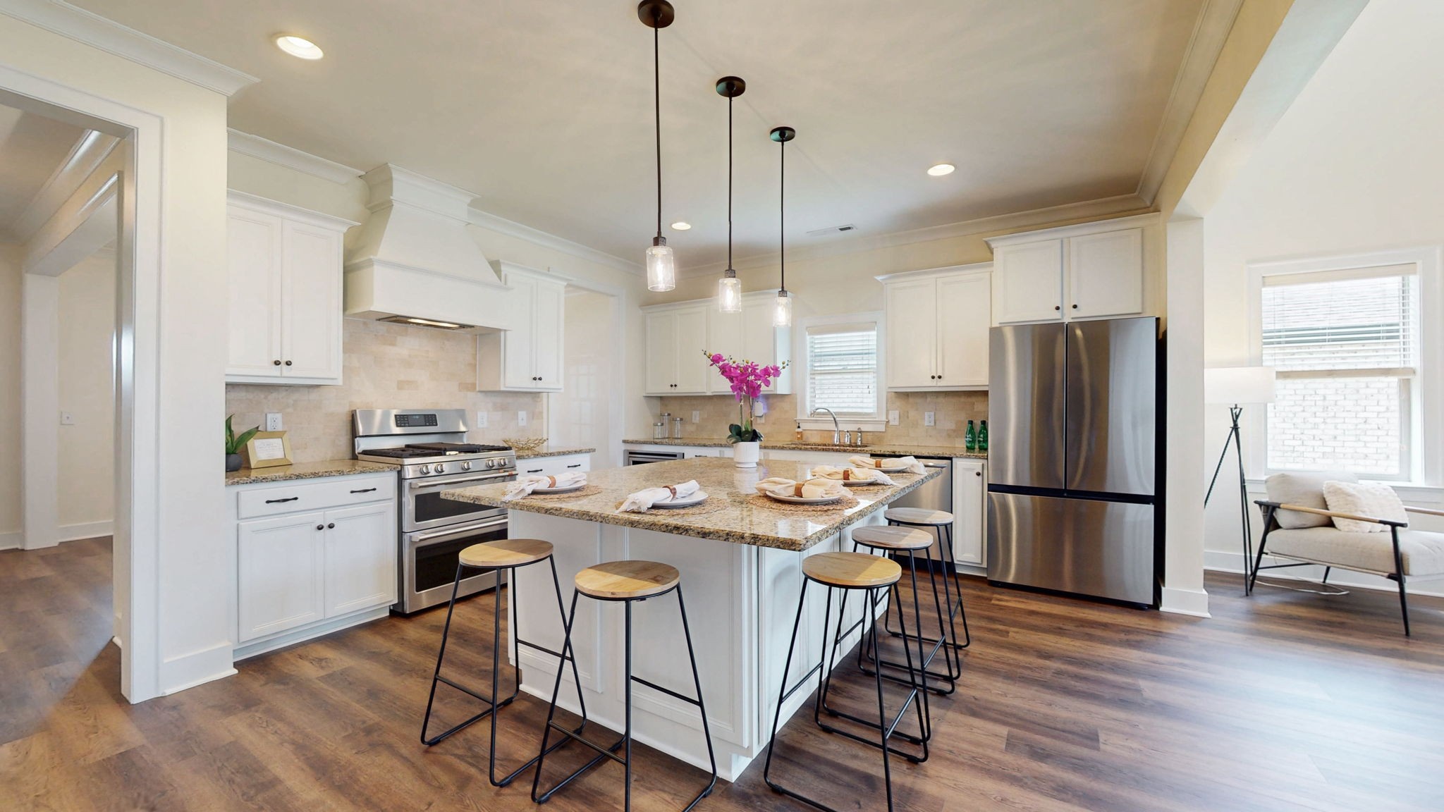 a kitchen with stainless steel appliances granite countertop a refrigerator a stove a sink dishwasher a refrigerator and a dining table with wooden floor