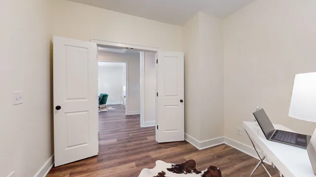an empty room with chandelier fan and windows