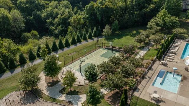 an aerial view of a residential houses with outdoor space and trees