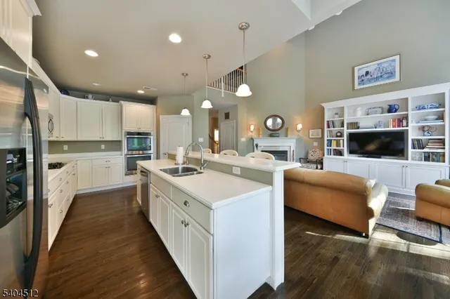 a kitchen with stainless steel appliances kitchen island granite countertop a refrigerator a stove a sink dishwasher and white countertops with wooden floor