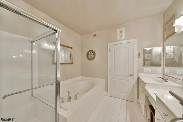 a bathroom with a tub shower sink and mirror