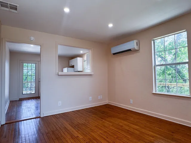 a view of an empty room with wooden floor and a window