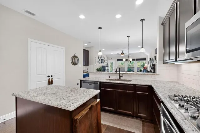a kitchen with stainless steel appliances granite countertop a sink a stove and a wooden floors