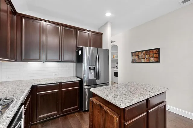 a kitchen with stainless steel appliances granite countertop a refrigerator and a stove top oven