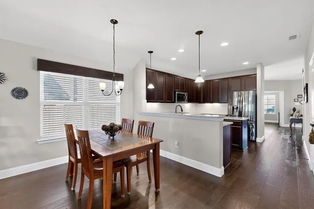 a kitchen with stainless steel appliances kitchen island granite countertop a stove a refrigerator a kitchen island a dining table and chairs with wooden floor