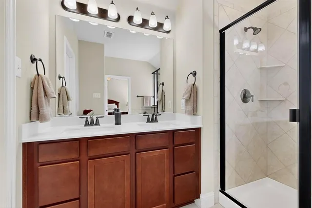 a bathroom with a double vanity sink mirror and shower