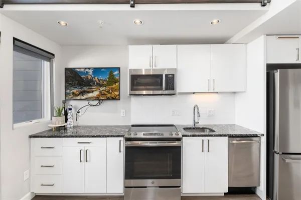 a kitchen with granite countertop a refrigerator stove and microwave