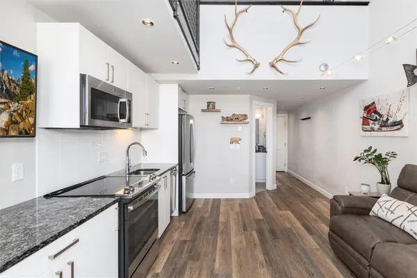 a kitchen with granite countertop a stove a sink and a refrigerator