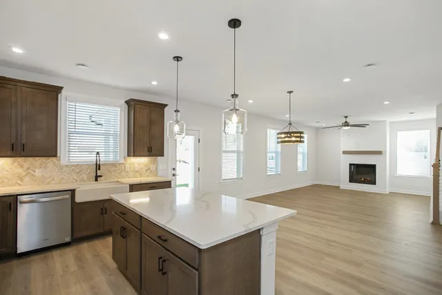 a kitchen with stainless steel appliances granite countertop a sink a kitchen island a stove and a wooden floors