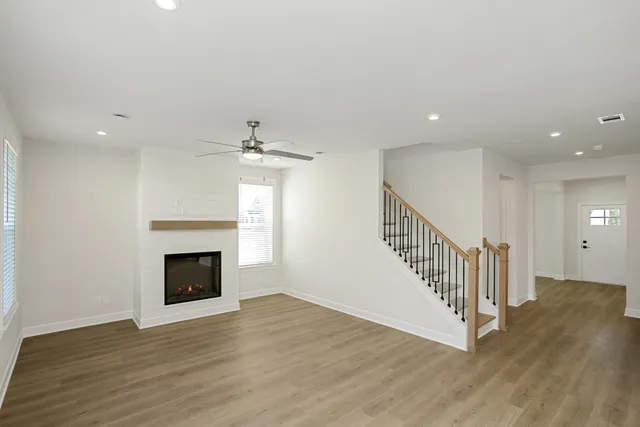 a view of an empty room with wooden floor fireplace and a window