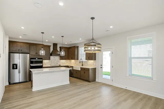 a view of a kitchen with stainless steel appliances granite countertop a sink and a wooden floor
