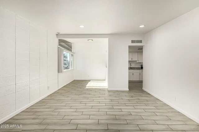 a view of an empty room with wooden floor and closet