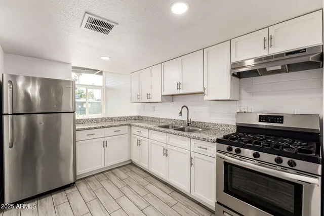 a kitchen with granite countertop white cabinets and a stove