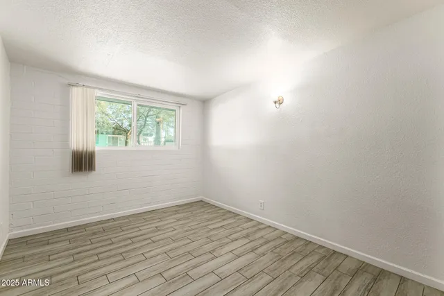 a view of an empty room with wooden floor and closet