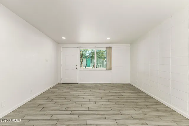 a view of empty room with wooden floor and kitchen