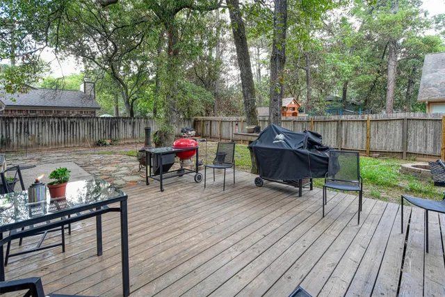 a view of deck with table and chairs potted plants with wooden floor and fence