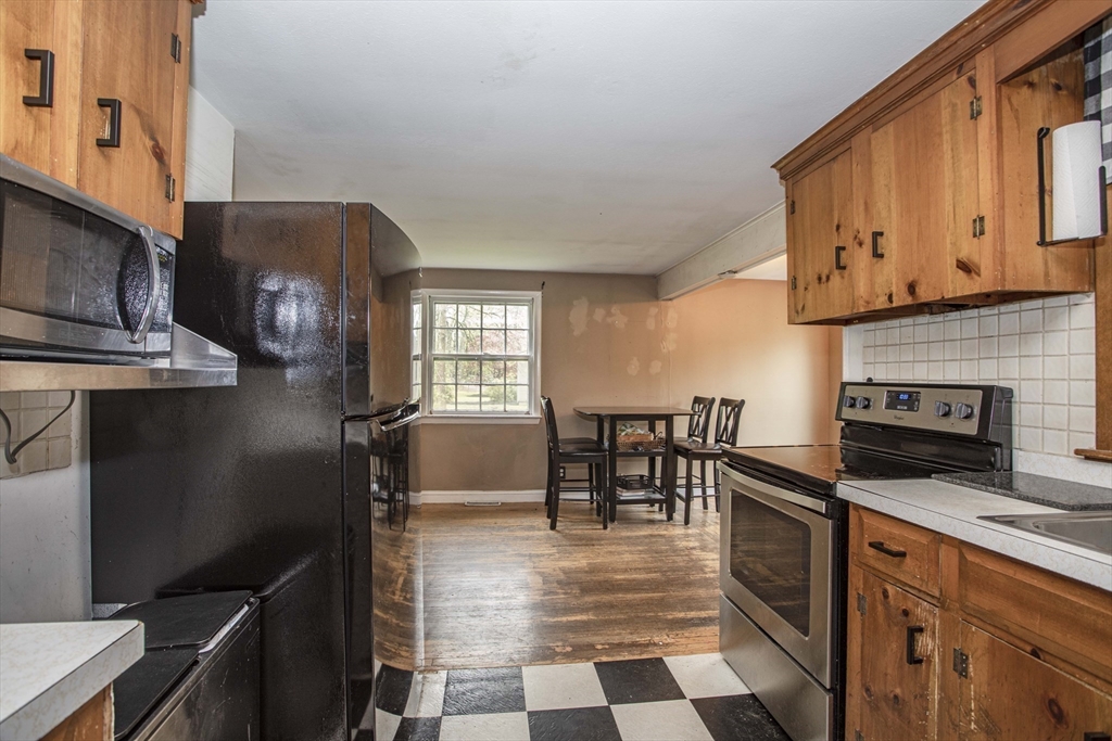 175 Summer Street Norwell, MA 02061 - Photo 12 of 29 a kitchen with stainless steel appliances granite countertop a refrigerator a stove a sink a dining table and chairs with wooden floor