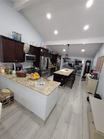 a kitchen with stainless steel appliances granite countertop a stove a sink a refrigerator and chairs