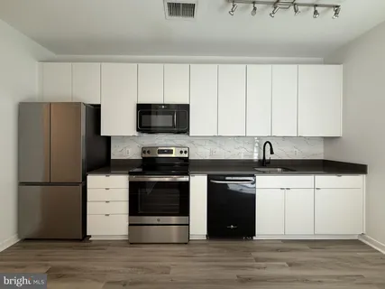 a kitchen with stainless steel appliances white cabinets and wooden floor