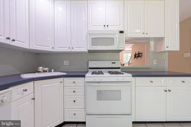 a kitchen with granite countertop white cabinets and white appliances