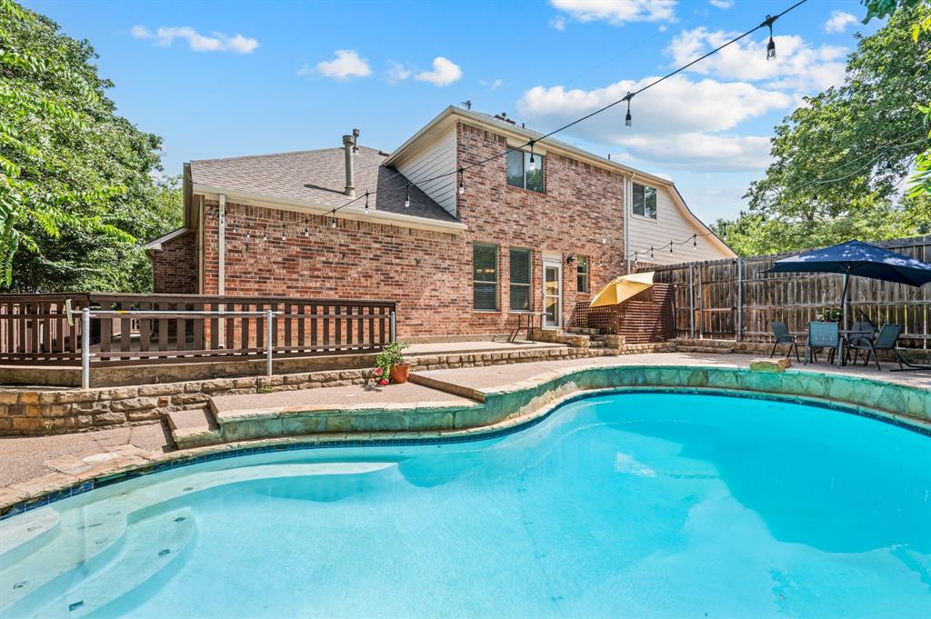808 Briar Ridge Drive Keller, TX 76248 - Photo 37 of 40 Curved inground pool with stone coping, a brick exterior home, and an elevated wood deck
