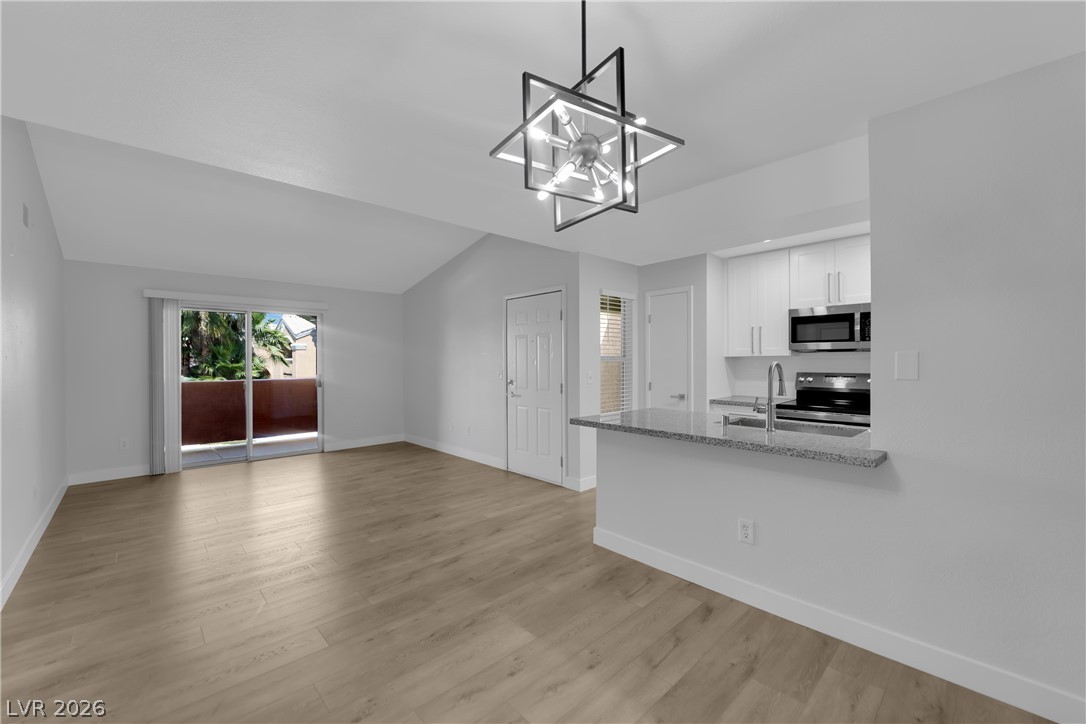 8101 West Flamingo Road, Unit 2152 Las Vegas, NV 89147 - Photo 12 of 45 A vibrant living area with vaulted ceilings, featuring an open kitchen and an outdoor balcony.