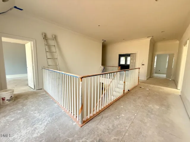 a view of a hallway to a livingroom with wooden floor and stairs