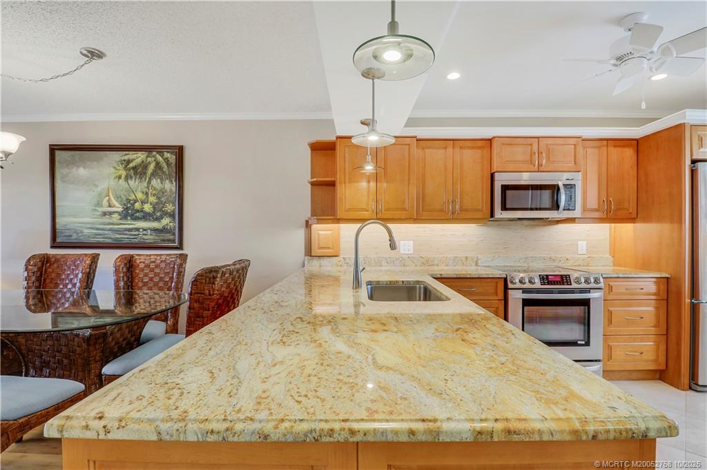 1866 Southwest Palm City Road, Unit 204 Stuart, FL 34994 - Photo 4 of 56 a kitchen with stainless steel appliances granite countertop a sink wooden cabinets and a granite counter top