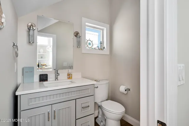 a bathroom with a toilet a sink a mirror a vanity and a window