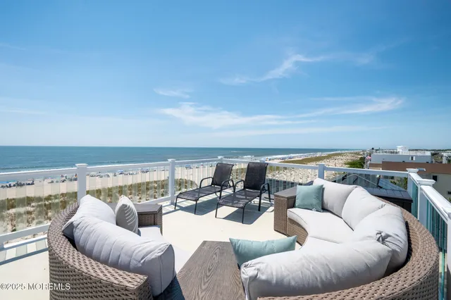 a view of roof deck with seating space and ocean view