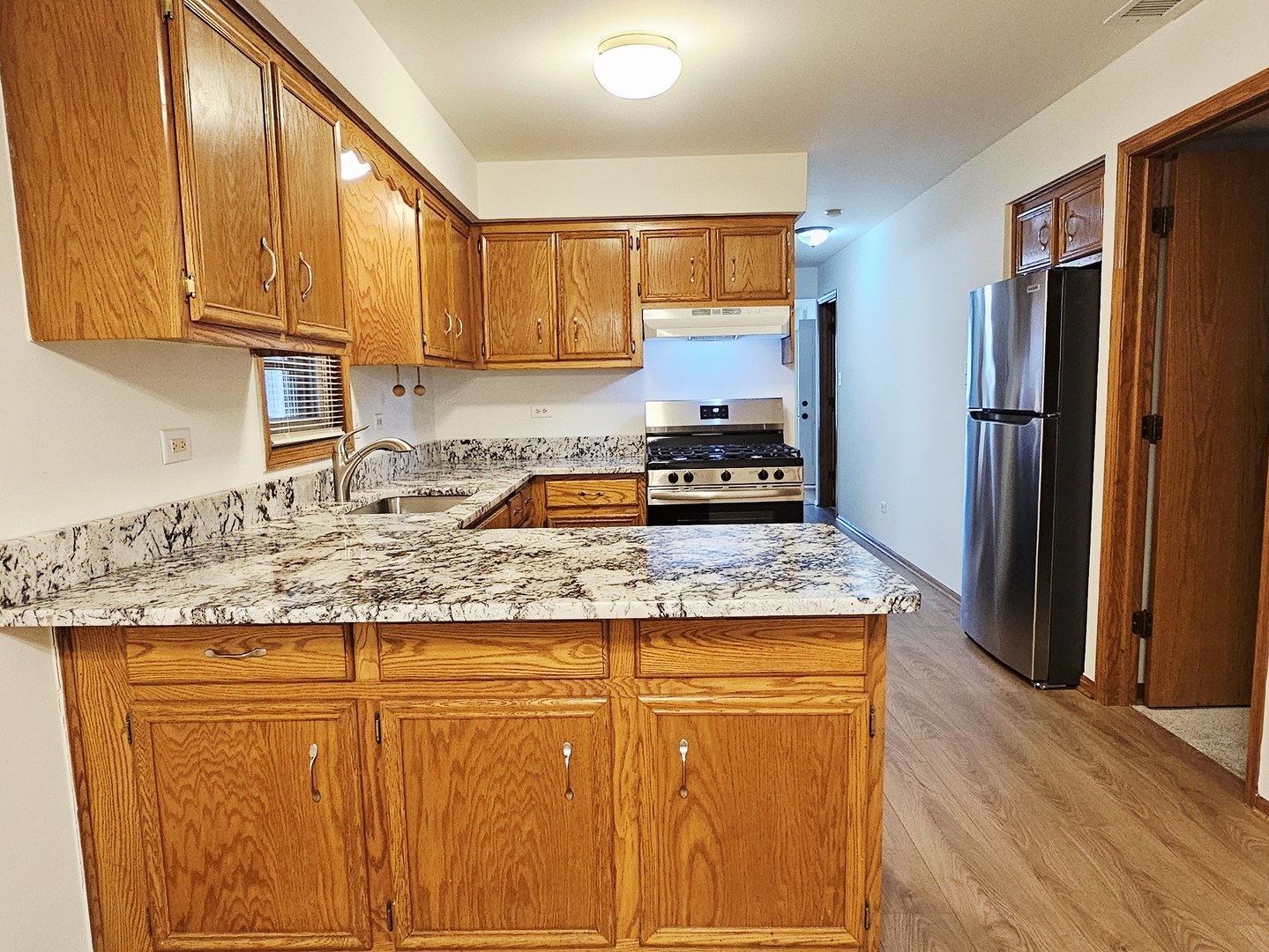 5324 Long Avenue, Unit 1 Chicago, IL 60638 - Photo 8 of 18 a kitchen with kitchen island granite countertop wooden cabinets a refrigerator and a sink