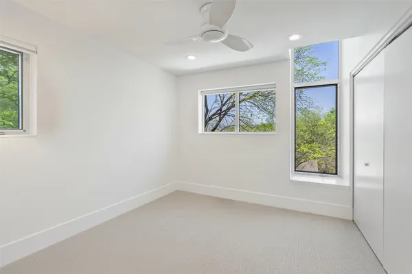 an empty room with windows and a ceiling fan