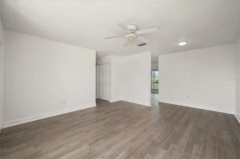 an empty room with wooden floor fan and windows