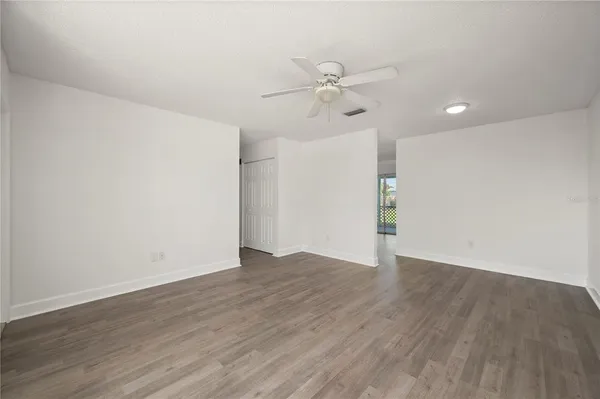 an empty room with wooden floor fan and windows
