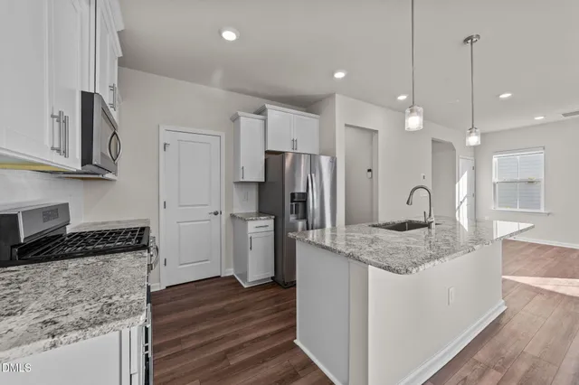 a kitchen with stainless steel appliances granite countertop a sink refrigerator and cabinets