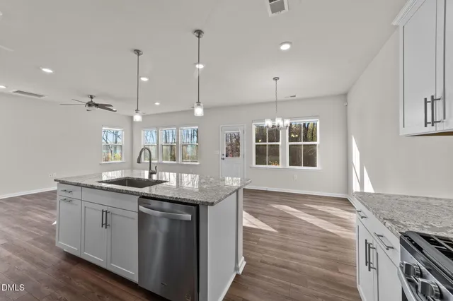 a kitchen with stainless steel appliances granite countertop a sink a stove and a wooden floors