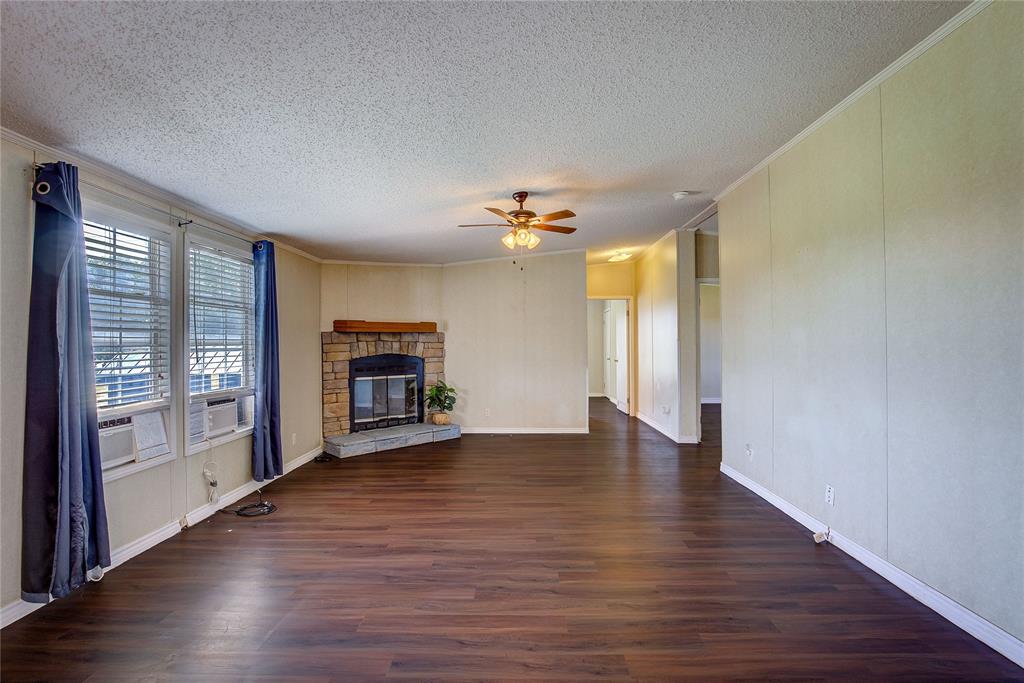 3077 Pecan Court Princeton, TX 75407 - Photo 16 of 37 an empty room with wooden floor fireplace and windows