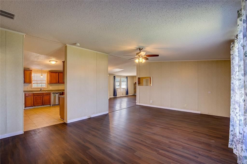 3077 Pecan Court Princeton, TX 75407 - Photo 10 of 37 a view of an empty room with wooden floor and a kitchen