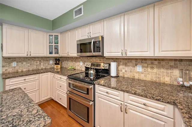 a kitchen with granite countertop white cabinets and stainless steel appliances