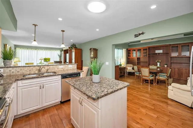 a kitchen with granite countertop kitchen island sink stove and white cabinets