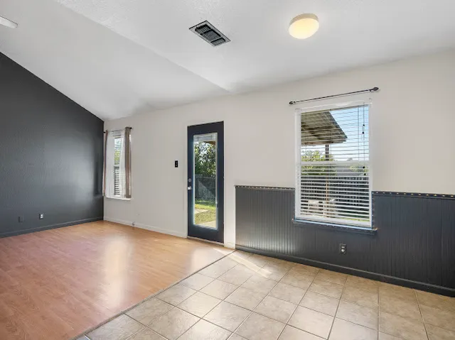 a view of an empty room with window and wooden floor