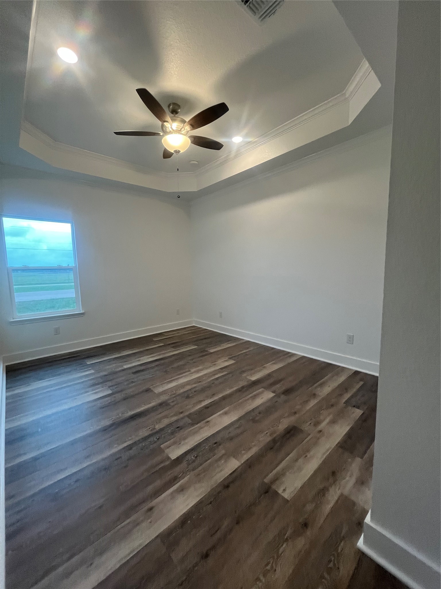 33416 FM 521 Road Angleton, TX 77515 - Photo 18 of 20 This room features elegant medium gray/wood water proof flooring, a tray ceiling with recessed lighting, and a ceiling fan. A large window allows for natural light, creating a bright and inviting space.