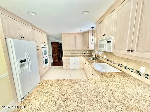 a large white kitchen with granite countertop a refrigerator and a sink