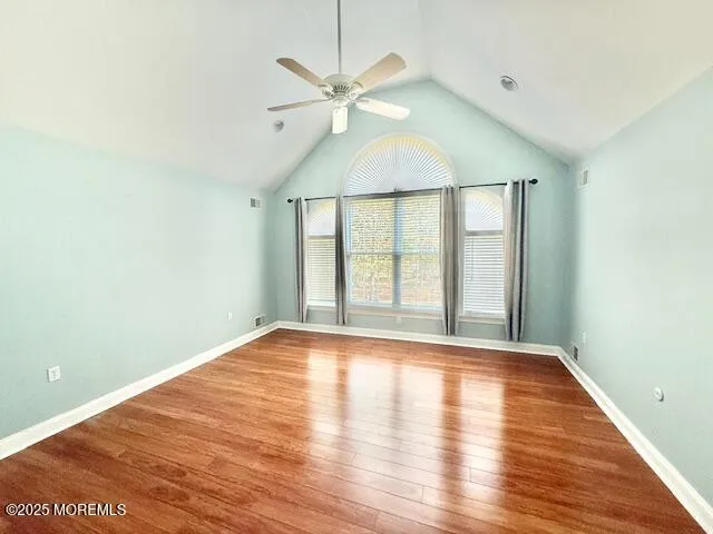 an empty room with wooden floor fan and windows