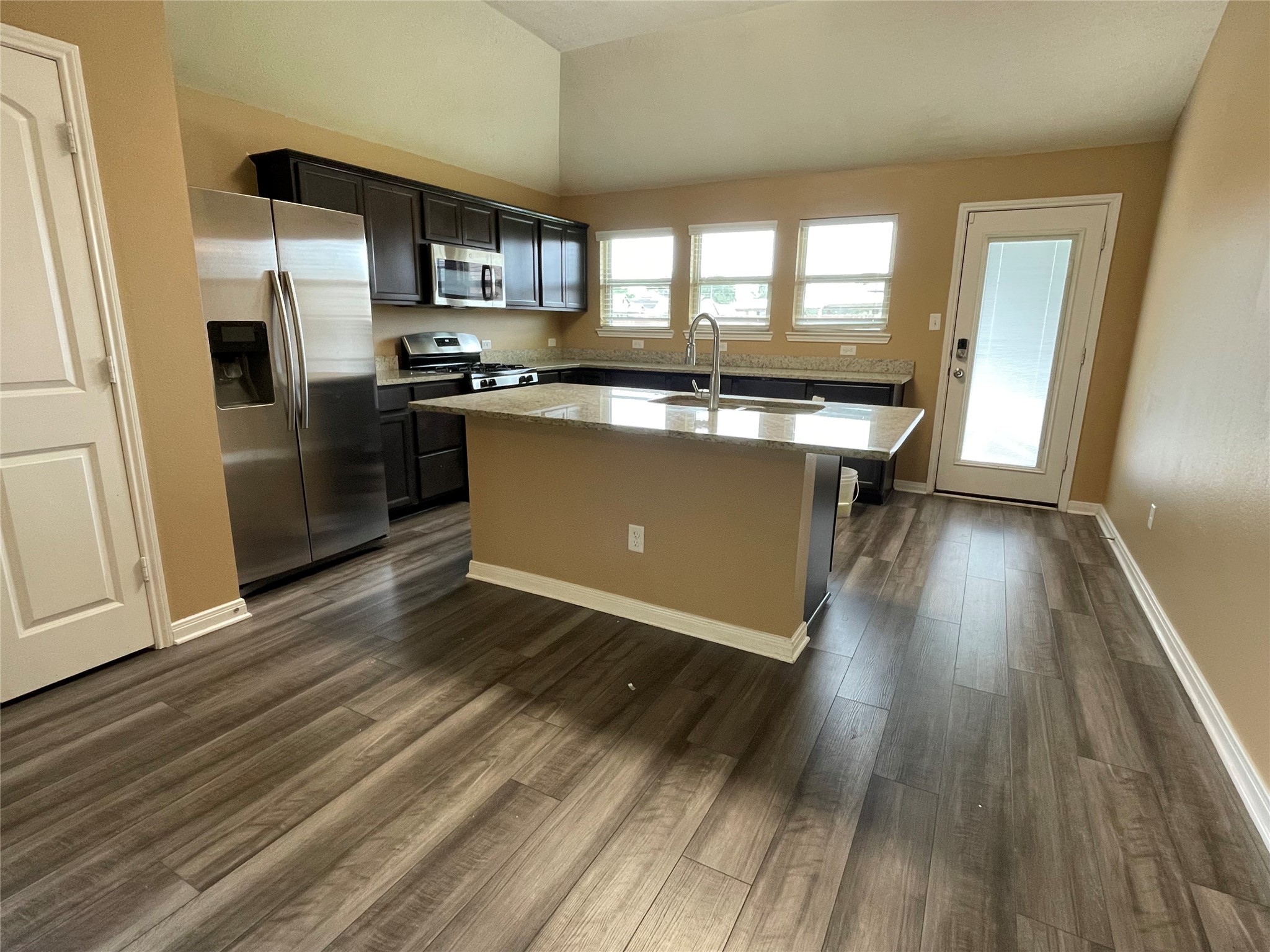 832 Mockingbird Street Navasota, TX 77868 - Photo 4 of 20 a kitchen with stainless steel appliances granite countertop a refrigerator a sink dishwasher a stove and white countertops with wooden floor