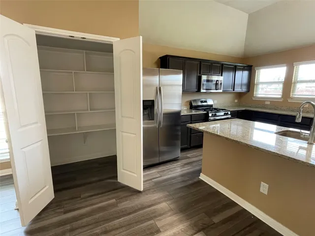 a kitchen with granite countertop a refrigerator and a stove top oven