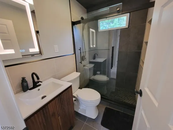 a bathroom with a sink a toilet a mirror and shower